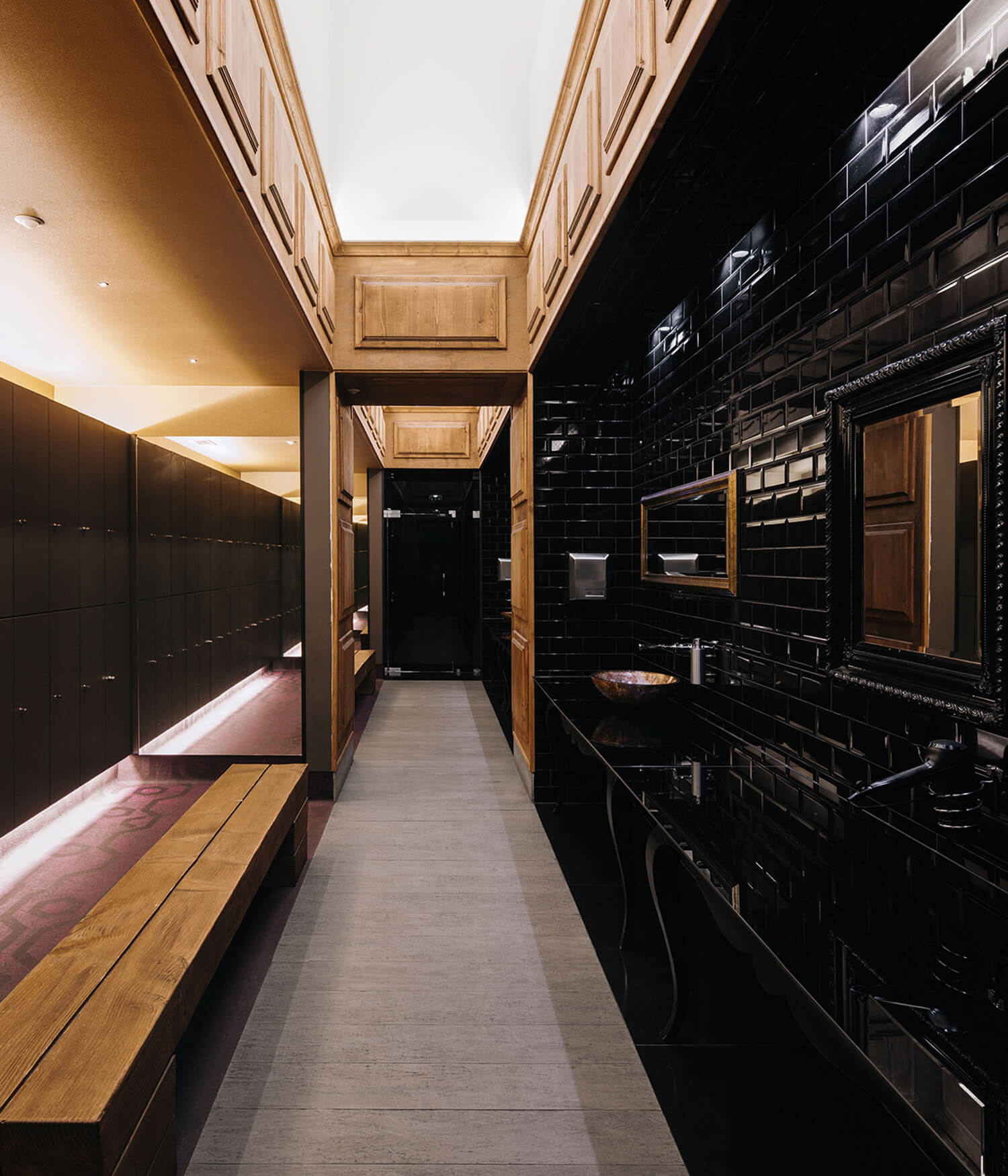 Perspective of the corridor contiguous to the lavatories and dryers, on the right, and to the dressing area of mirrored walls and backlit lockers, on the left.